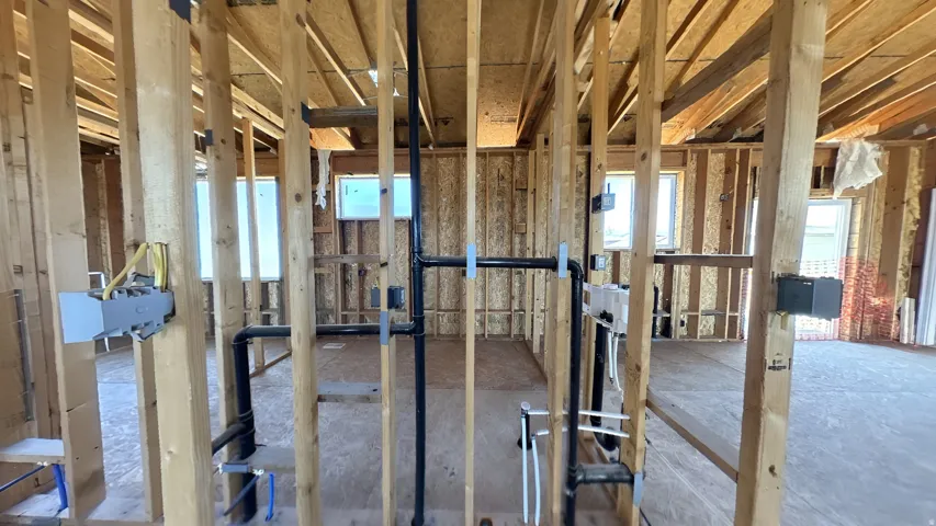 Framed interior space featuring exposed wooden studs, multiple windows, electrical boxes with wiring, and visible plumbing rough-ins, showcasing an early stage of construction
