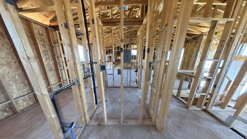 Unfinished interior framing revealing structural elements, electrical wiring, and plumbing