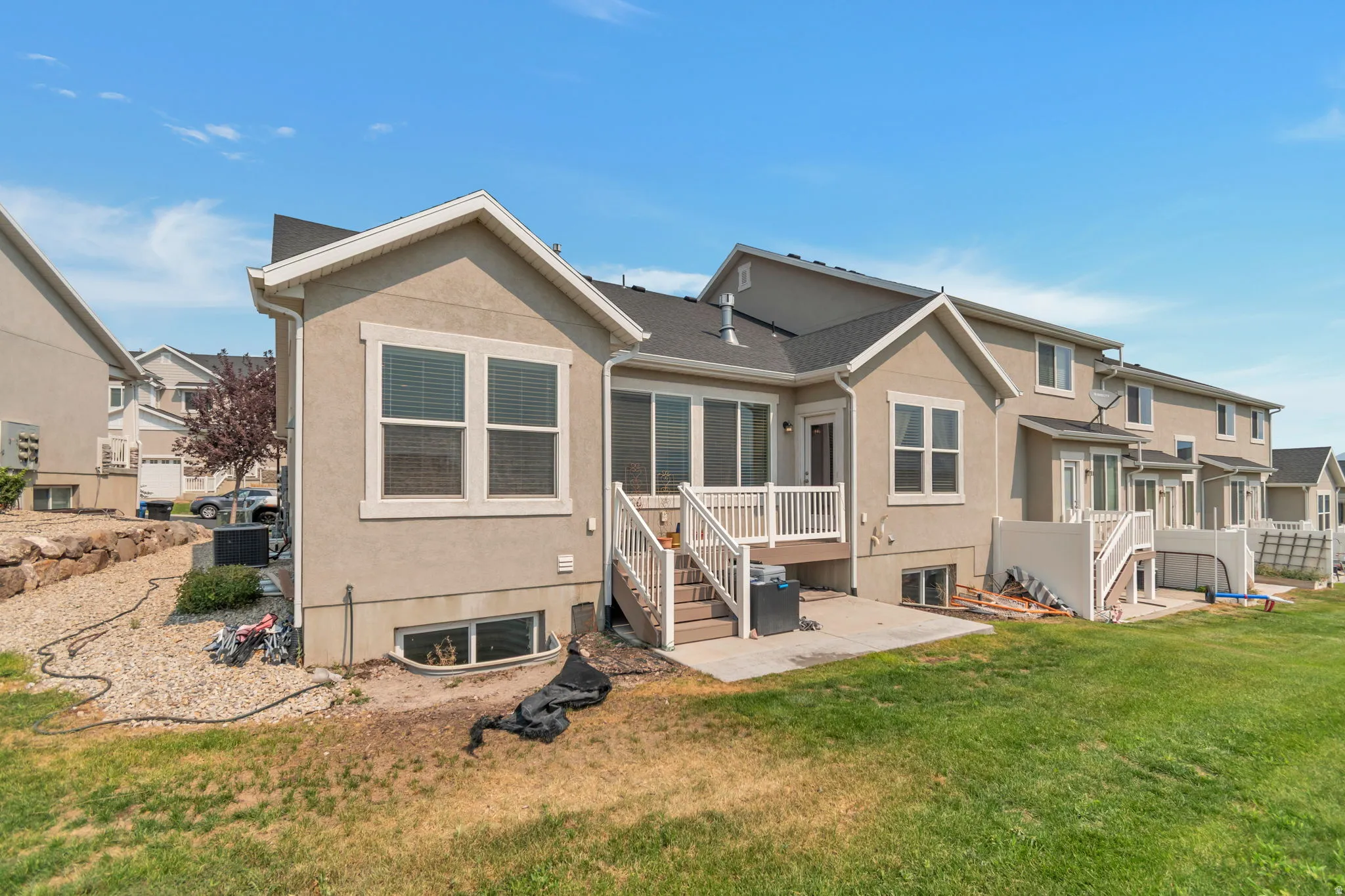 Rear exterior featuring a concrete patio, wood-finish decking with white railings, and a walk-out basement