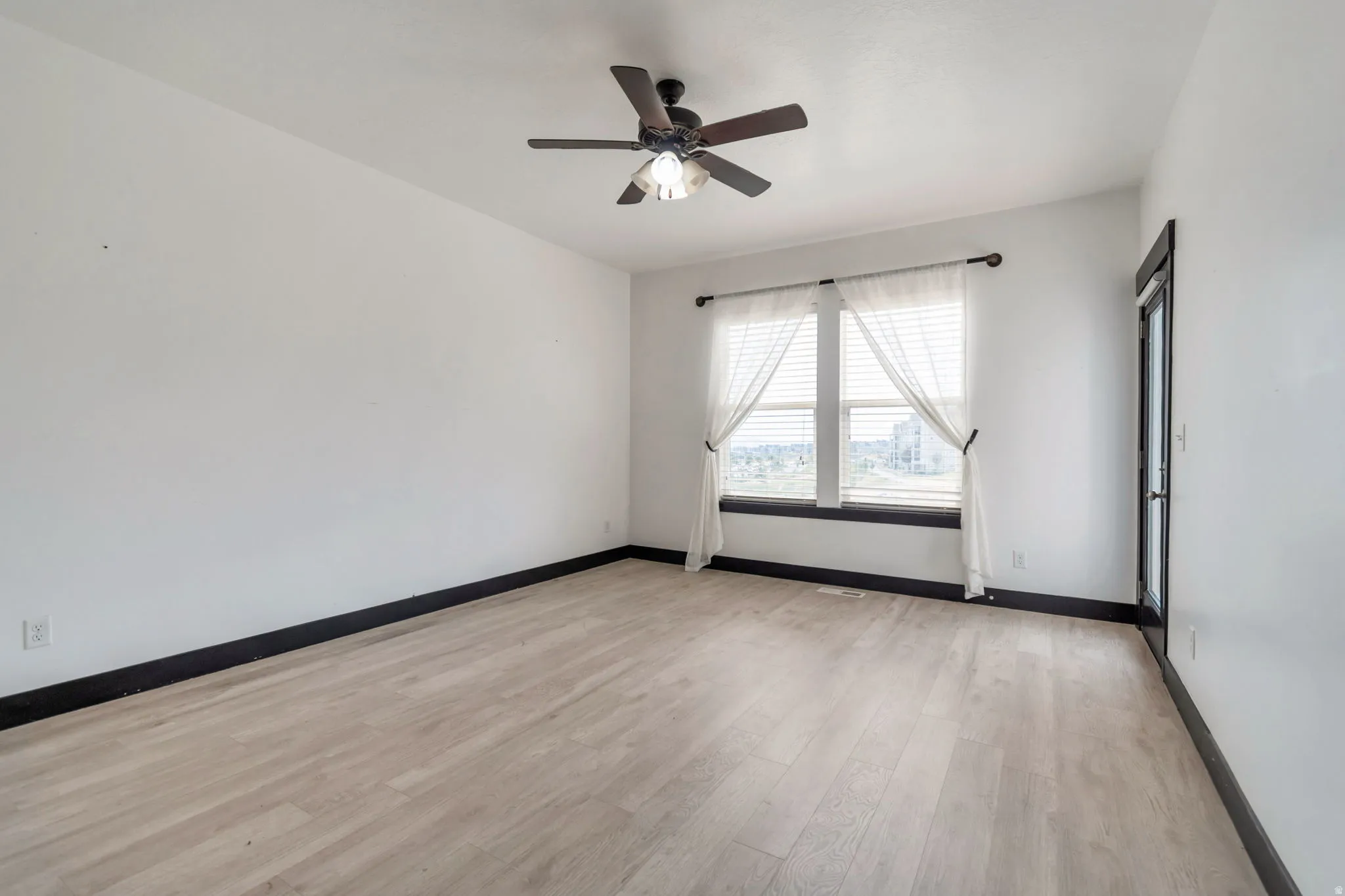 Room featuring wood-finish flooring, white walls, and dark trim