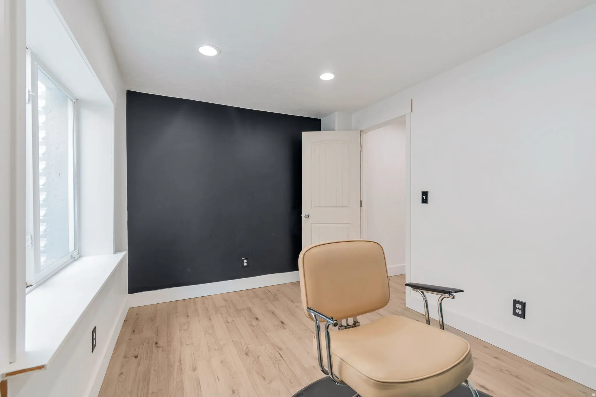 Room with wood-finish flooring, a dark accent wall, and recessed ceiling lighting