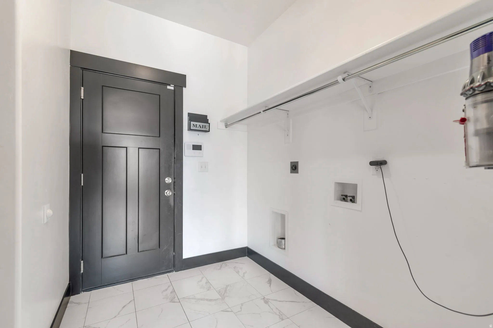 Utility space featuring a dark paneled door with contemporary hardware, white walls, and a matching dark baseboard