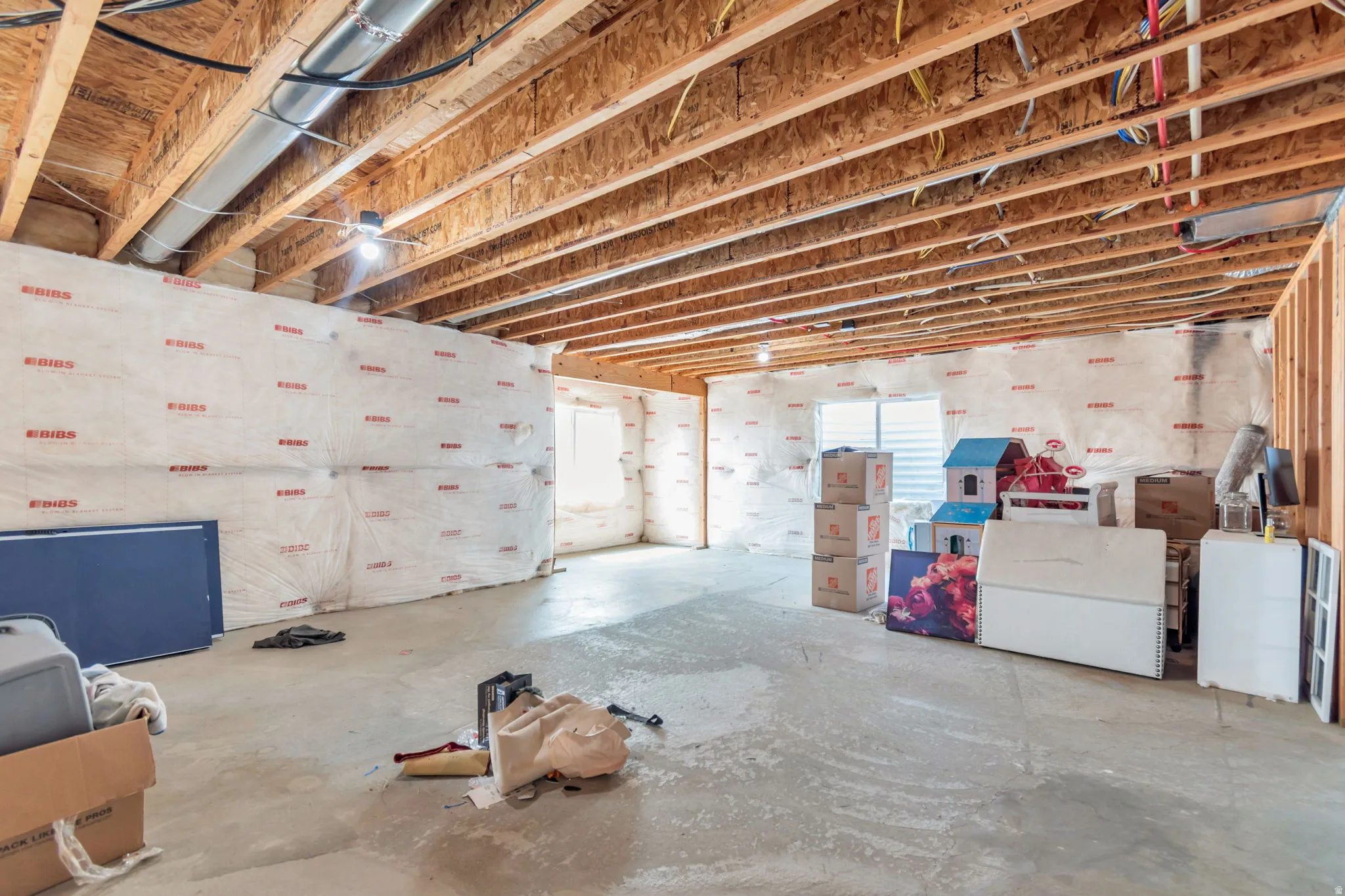 Spacious unfinished basement with exposed wood joists and concrete flooring