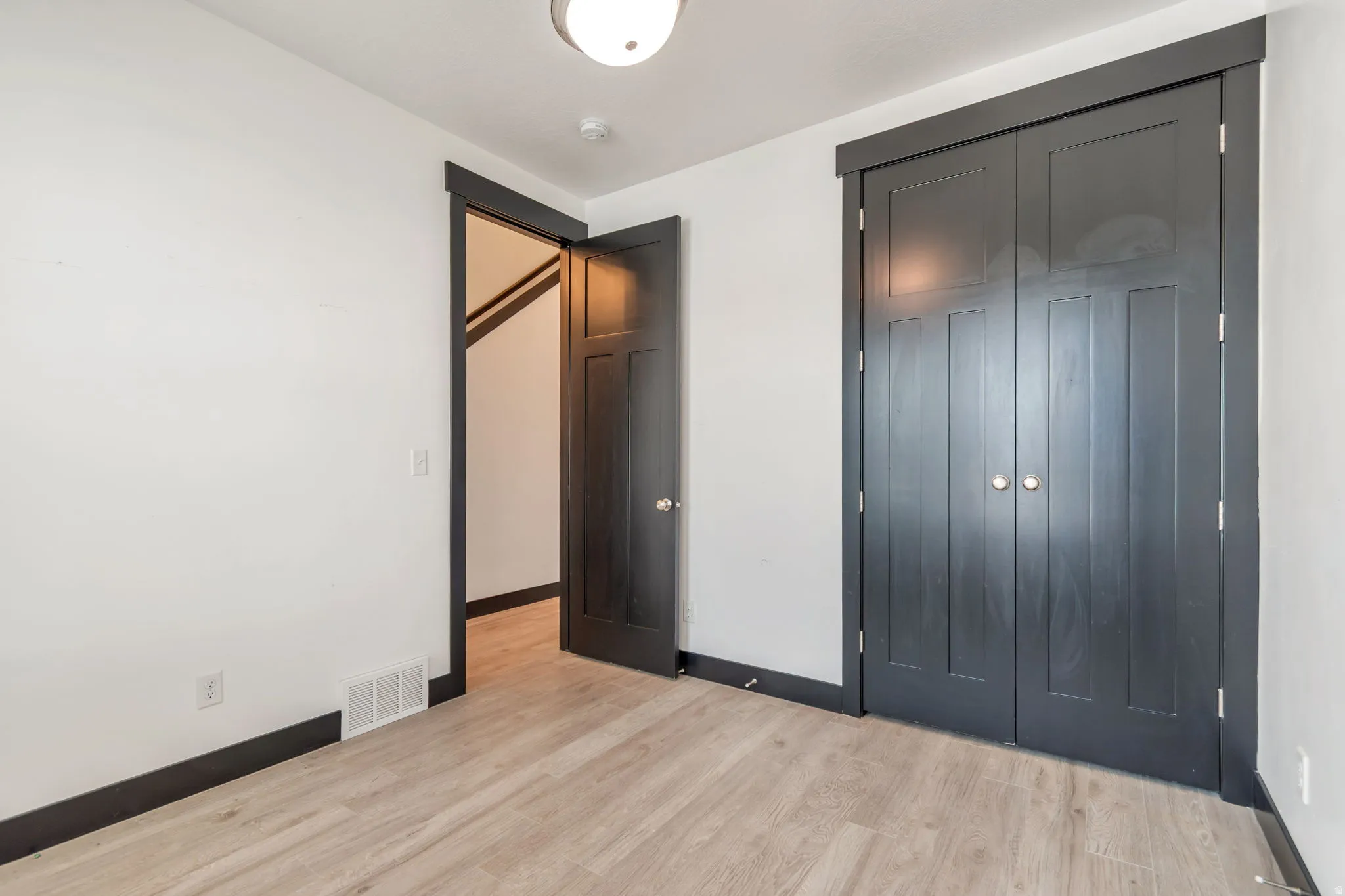 Room featuring light wood-finish flooring, white walls, and dark trim