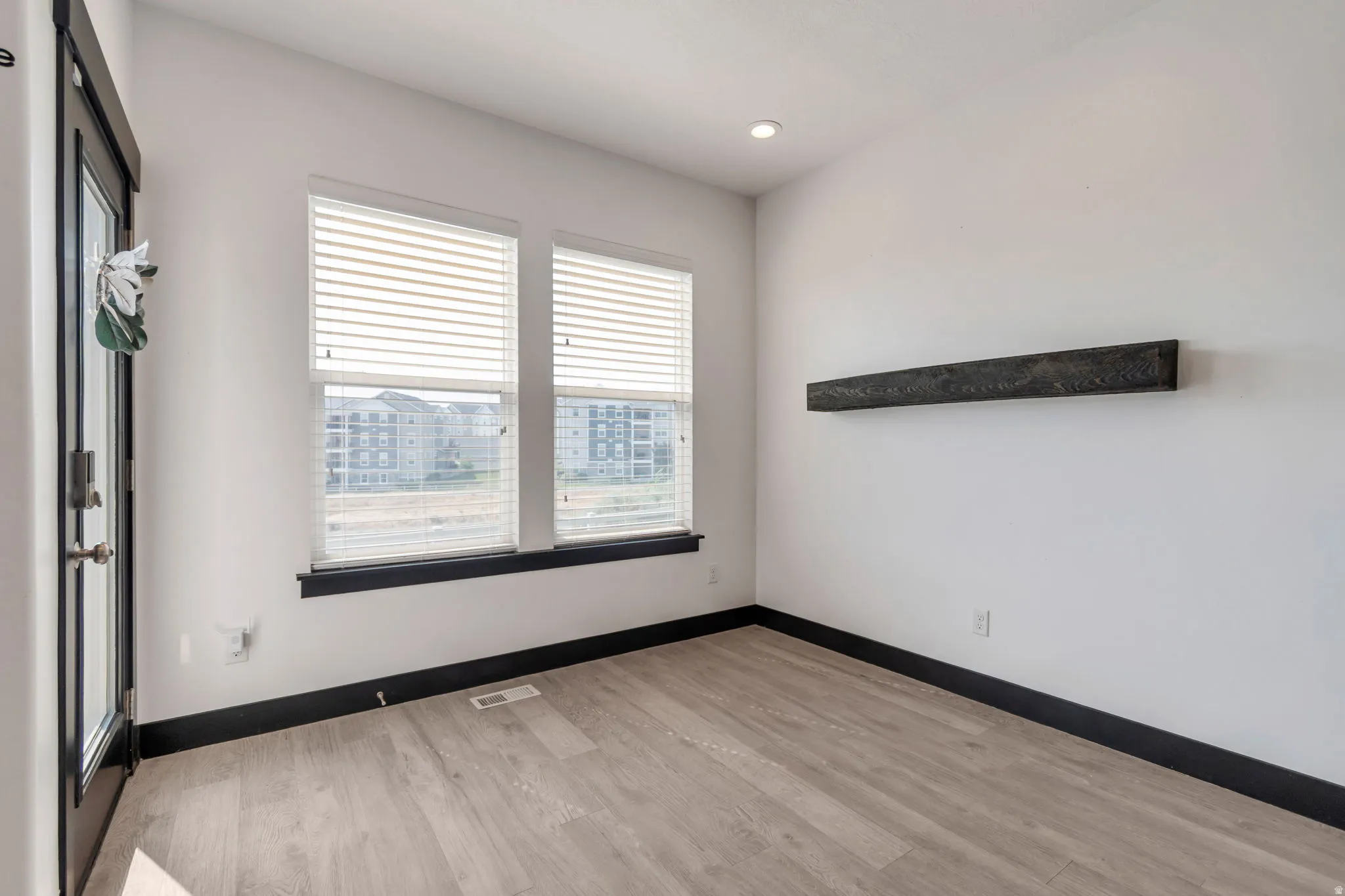 Light wood-finish flooring complements white walls with contrasting dark trim