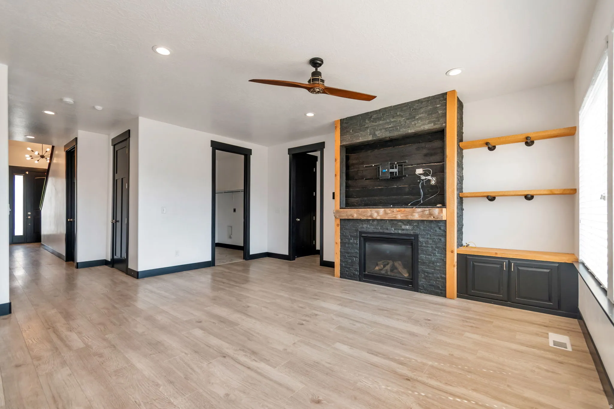 Living area featuring light wood-finish flooring, recessed lighting, and a dark wood-blade ceiling fan