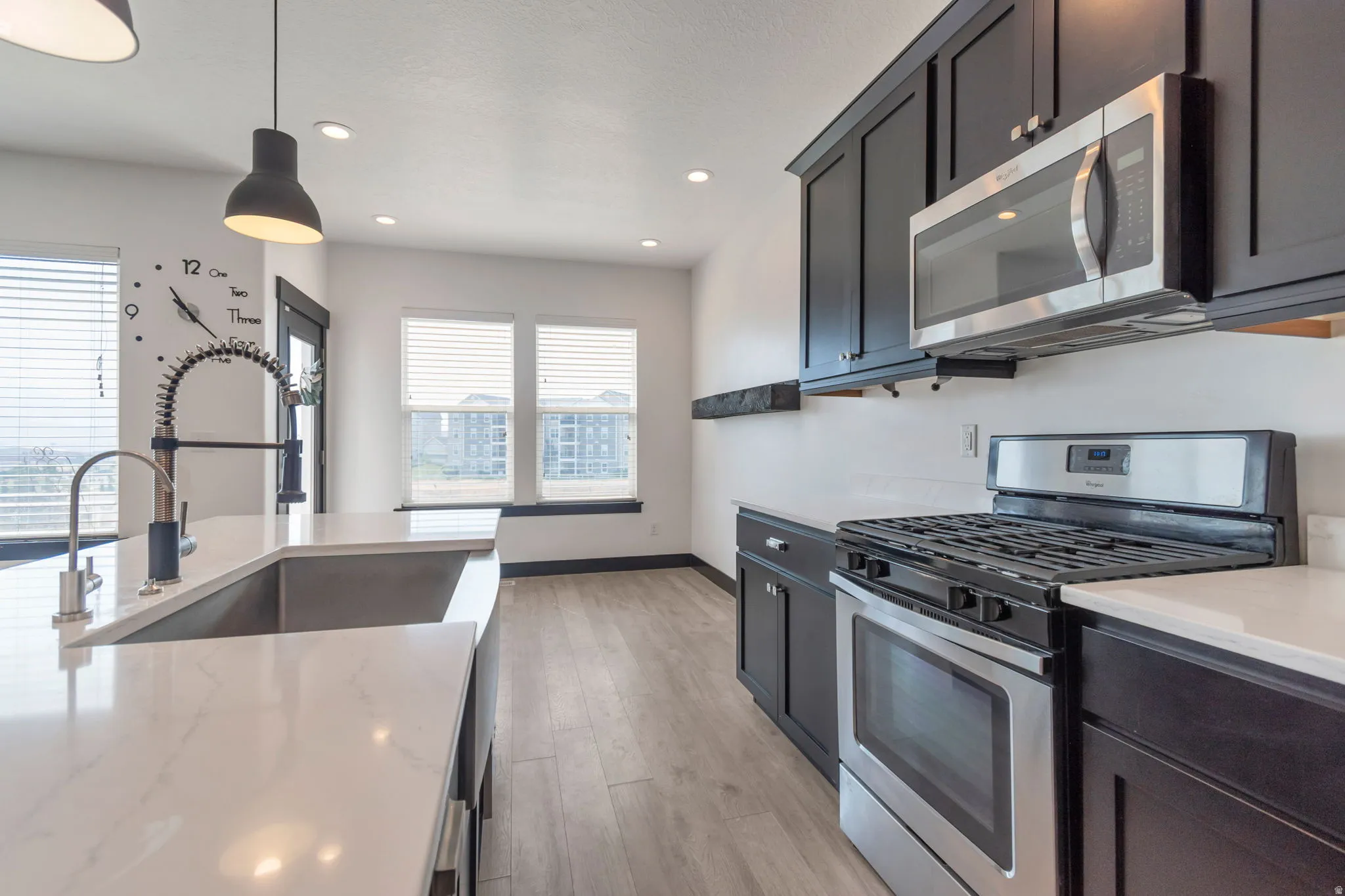 Kitchen featuring dark cabinetry, stainless steel appliances, white countertops, and wood-finish flooring