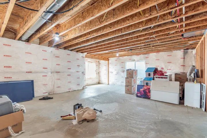 Spacious unfinished basement with exposed wood joists and concrete flooring