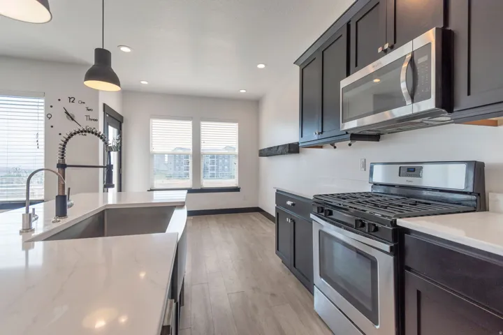 Kitchen featuring dark cabinetry, stainless steel appliances, white countertops, and wood-finish flooring