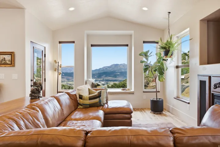 Spacious room featuring vaulted ceilings, recessed lighting, and expansive windows showcasing mountain scenery