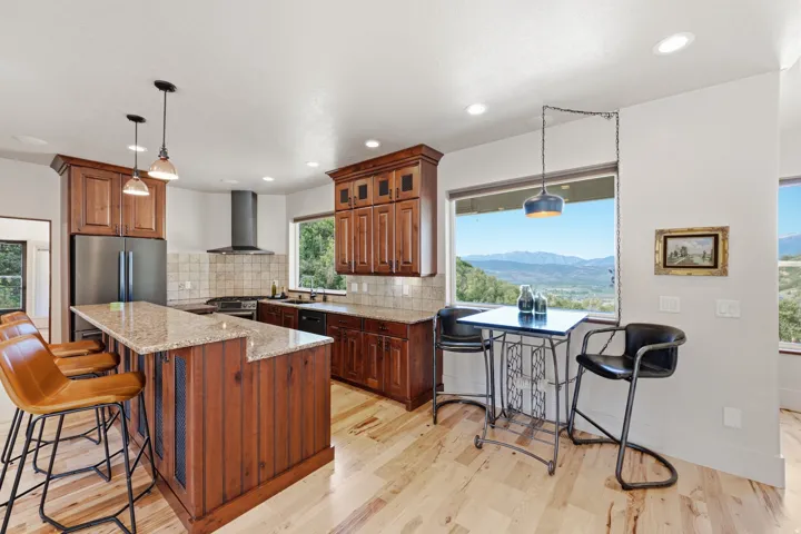 Kitchen featuring light wood-finish flooring, recessed lighting, and a substantial island with a natural stone countertop and wood paneling
