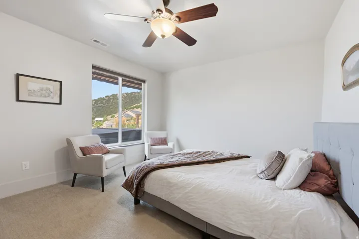 Bright interior space featuring a large window with mountain scenery, neutral wall tones, and a ceiling fan with integrated lighting