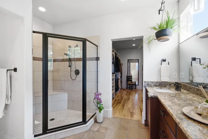 Spacious bathroom featuring a glass-enclosed shower with a built-in bench, neutral tile, and a decorative accent band