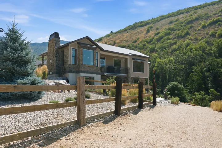 Mountain-side residence featuring a stone chimney, multiple bay windows, and a multi-level structure