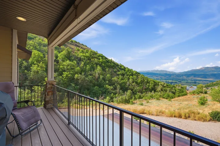 Covered outdoor deck with composite wood-finish flooring, black metal railings, and a stone-clad column