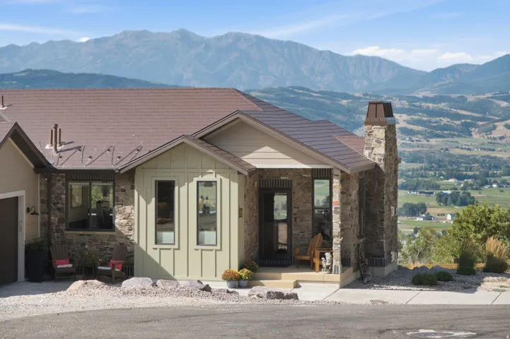 Stone and siding exterior with a brown roof and a prominent stone chimney