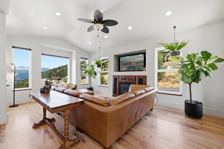 Spacious living area featuring light wood-finish flooring and a vaulted ceiling with recessed lighting