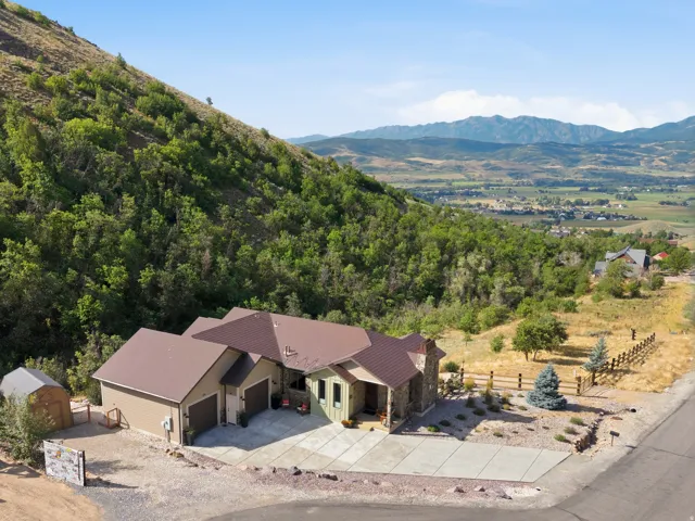 Architectural style featuring stone and siding, multi-vehicle concrete driveway, and attached two-car garage