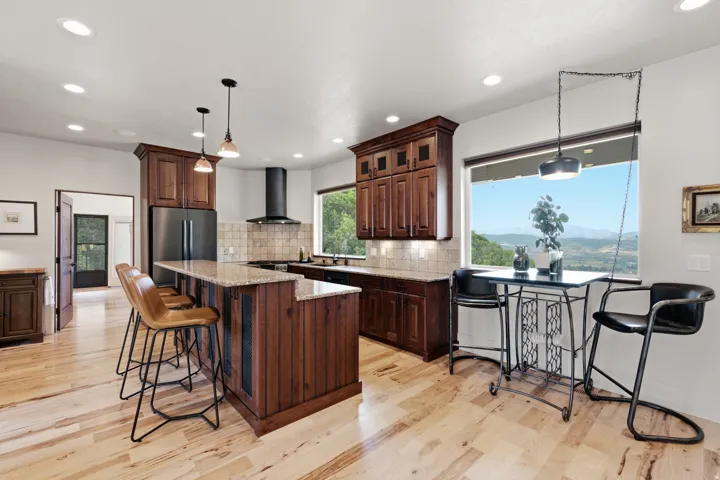 Kitchen featuring hardwood flooring, recessed lighting, and a kitchen island with a stone countertop