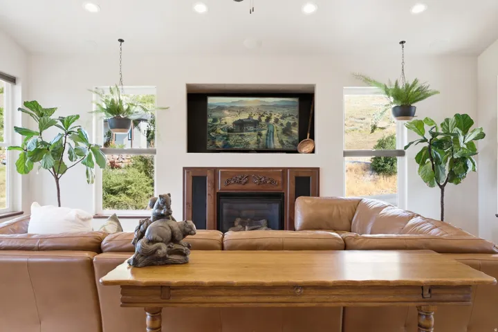 Living area featuring a central fireplace with an ornate wood mantel, a recessed media alcove, and multiple windows