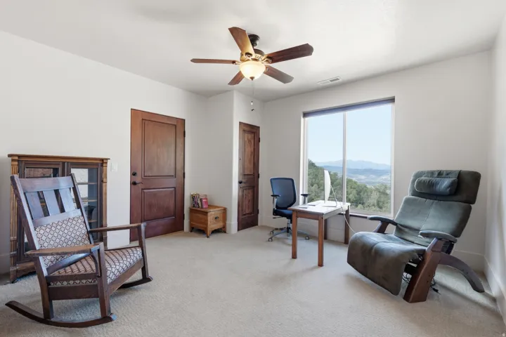 Spacious room with a large picture window, two panel wood doors, and a ceiling fan with integrated lighting