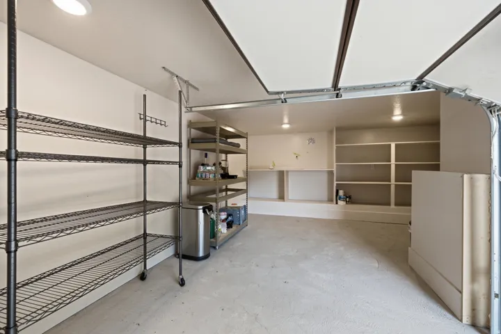 Garage interior featuring built-in shelving, painted concrete flooring, recessed lighting, and an overhead garage door mechanism