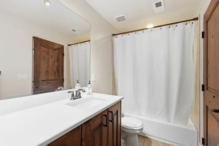 Bathroom featuring a wood-finish vanity with a white countertop and undermount sink