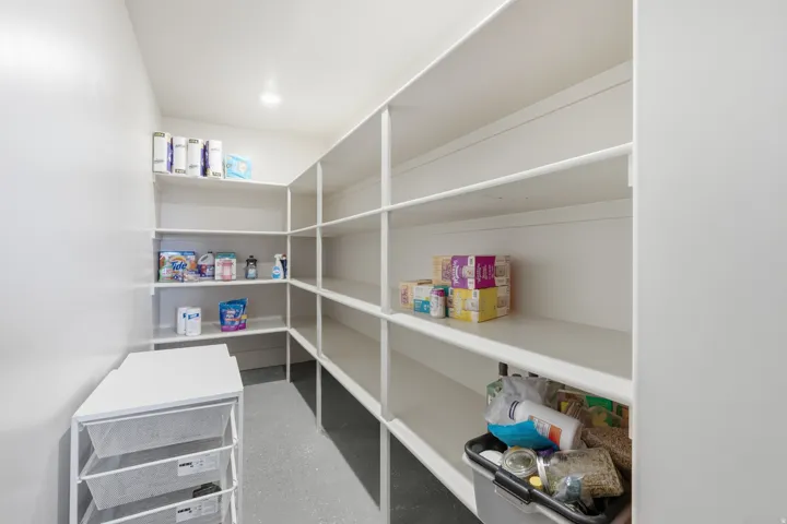 Spacious pantry featuring extensive wrap-around shelving, recessed lighting, and durable flooring