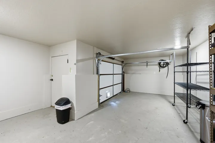 Spacious garage featuring a concrete floor, bright white walls, and a dedicated entry door