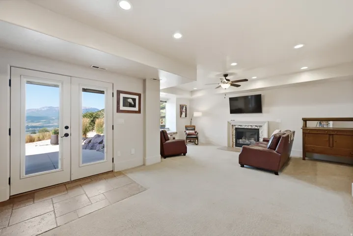 Spacious room featuring French doors, recessed lighting, and a stone fireplace with mantle
