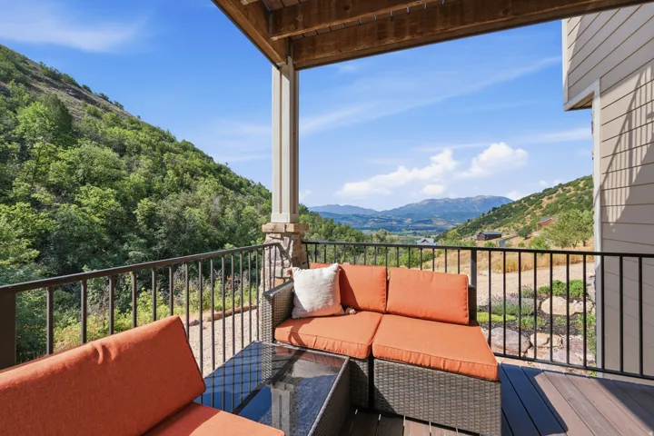 Expansive outdoor deck featuring wood-finish flooring, a stone-accented support column, and black metal railings