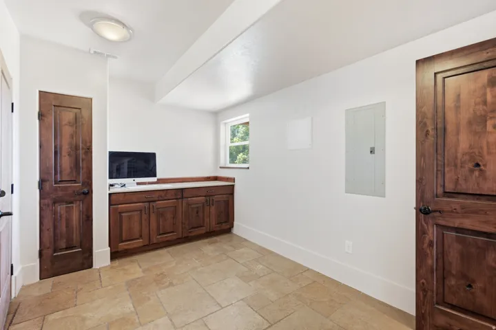 Stone tile flooring complements the built-in wood cabinetry with a light-toned countertop