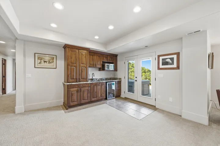 Built-in wet bar featuring wood cabinetry, stone countertops, and an undermount sink