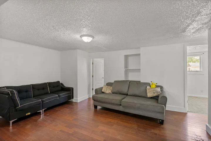 Spacious room featuring wood-finish flooring, white walls, and a ceiling-mounted light fixture
