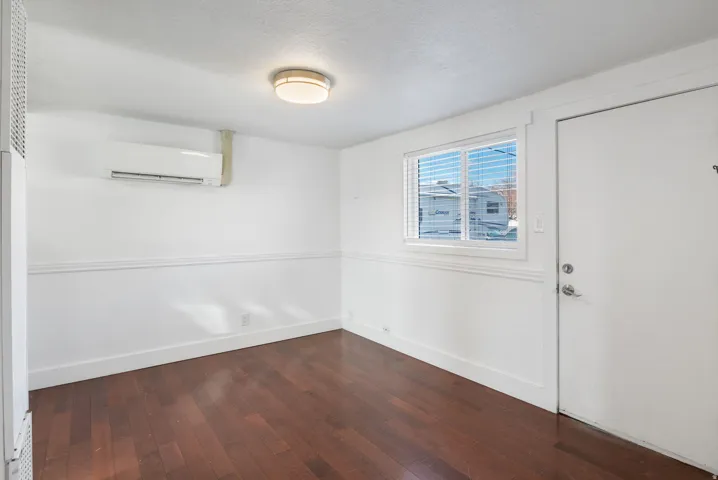 Interior room featuring dark wood-finish flooring, white walls with decorative molding, and a flush-mount ceiling light