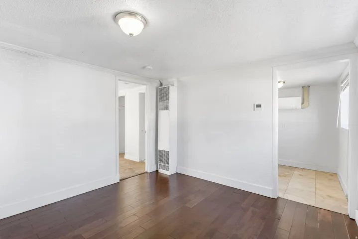 Room featuring dark wood-finish flooring, white walls, and a wall-mounted heater