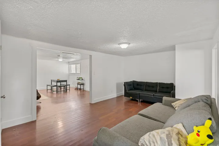Hardwood-style flooring extends throughout this spacious common area, featuring white walls and a ceiling-mounted light fixture