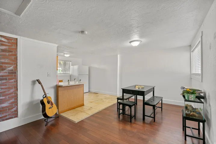 Open-concept living area featuring rich wood-finish flooring, a brick accent wall, and recessed lighting