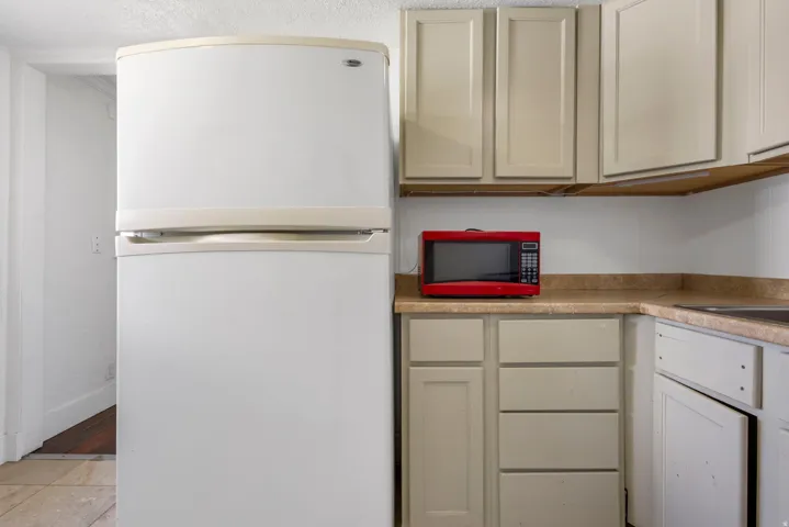 Kitchen area featuring a white refrigerator, light-toned cabinetry, laminate countertops, and a built-in sink