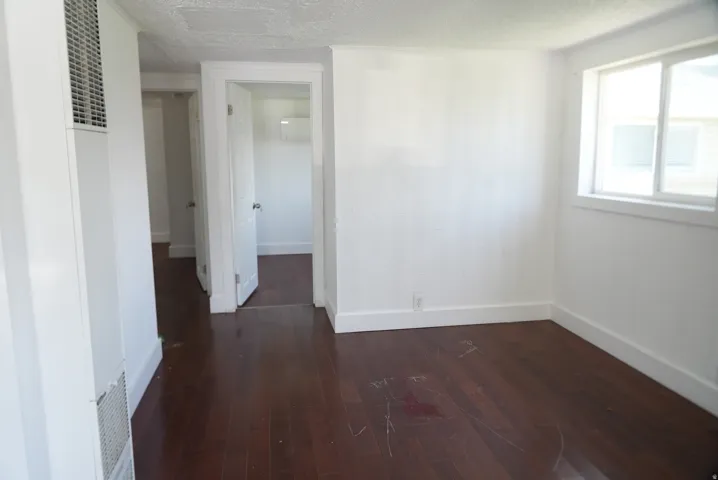Hardwood flooring throughout, white baseboards, and white walls