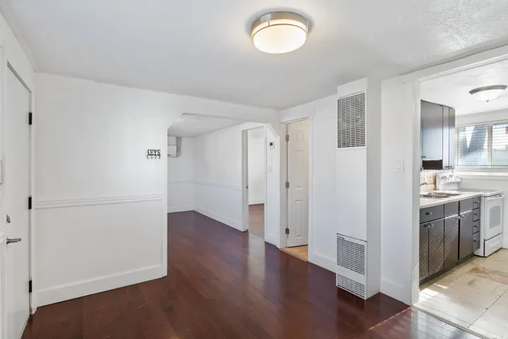 Wood-finish flooring extending from the entry into an arched doorway