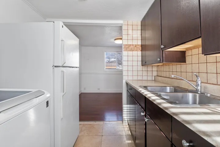 Kitchen featuring dark wood-finish cabinetry, a double basin stainless steel sink, and a tiled backsplash