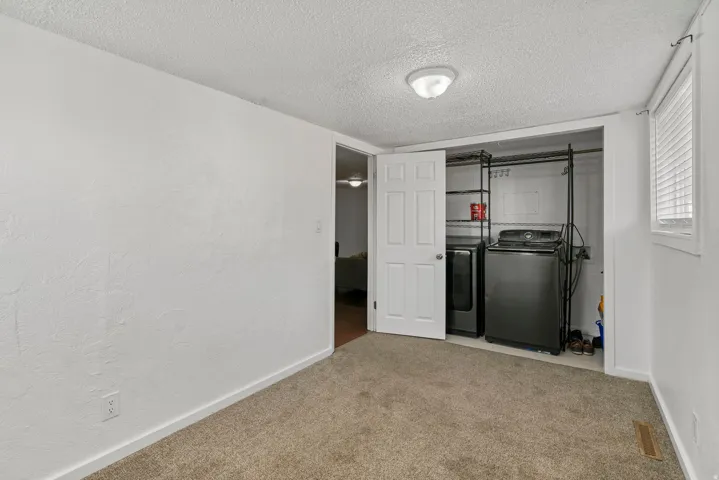 Laundry area featuring a side-by-side washer and dryer, open wire shelving, and overhead lighting