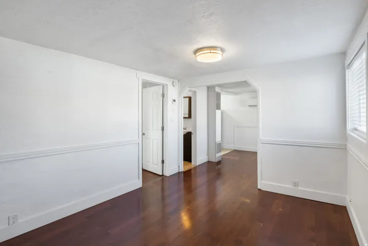 Rich wood-finish flooring complements white walls with wainscoting and trim