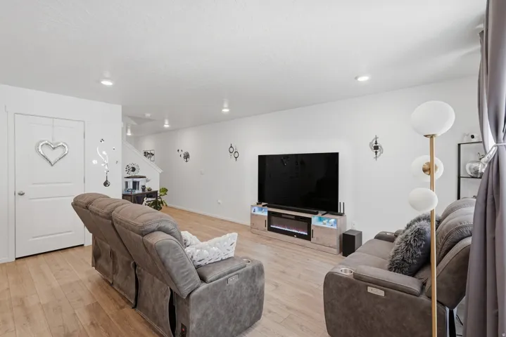 Living area featuring wood-finish flooring, recessed lighting, and a built-in media console with an electric fireplace