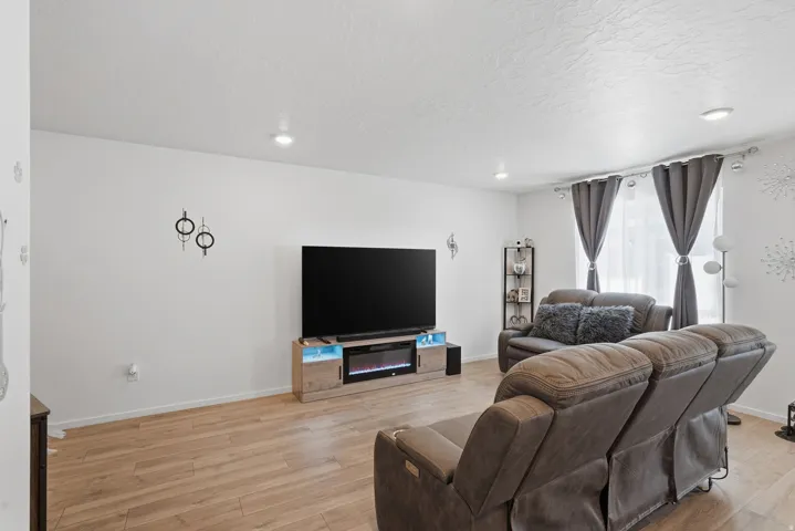 Open living area featuring wood-finish flooring, recessed lighting, and a window with privacy blinds