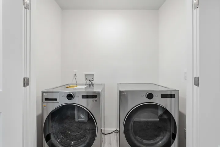 Dedicated laundry area featuring front-loading appliances, clean white walls, and a light-toned flooring