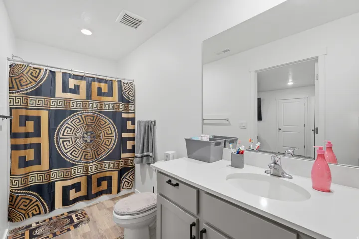 Bathroom featuring a single vanity with light countertop, integrated sink, and gray cabinetry with dark hardware