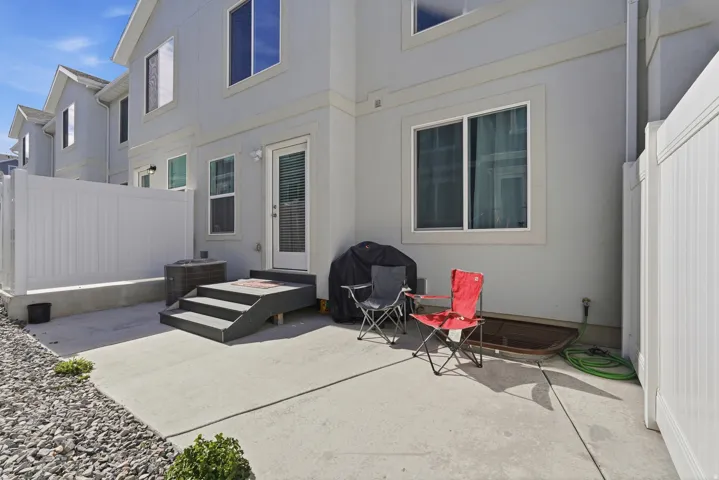 Private outdoor patio featuring concrete paving, white vinyl fencing, and direct exterior access
