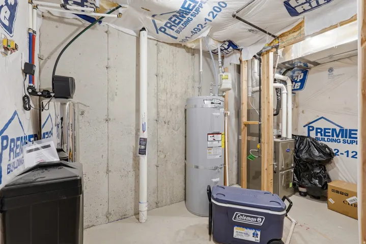 Unfinished utility area featuring a water heater, furnace, concrete walls, and visible plumbing